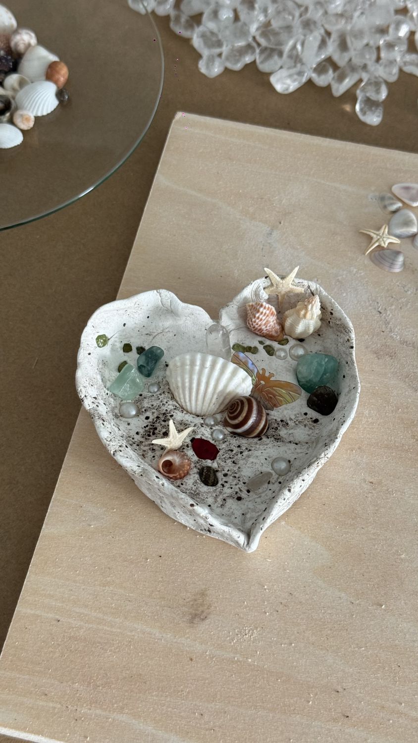 A heart-shaped stone clay dish set with seashells, starfish, pearls and green and clear crystals